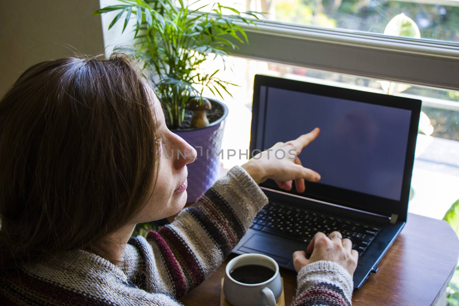 Woman working in office with digital tablet and notebook, writing and typing on the device