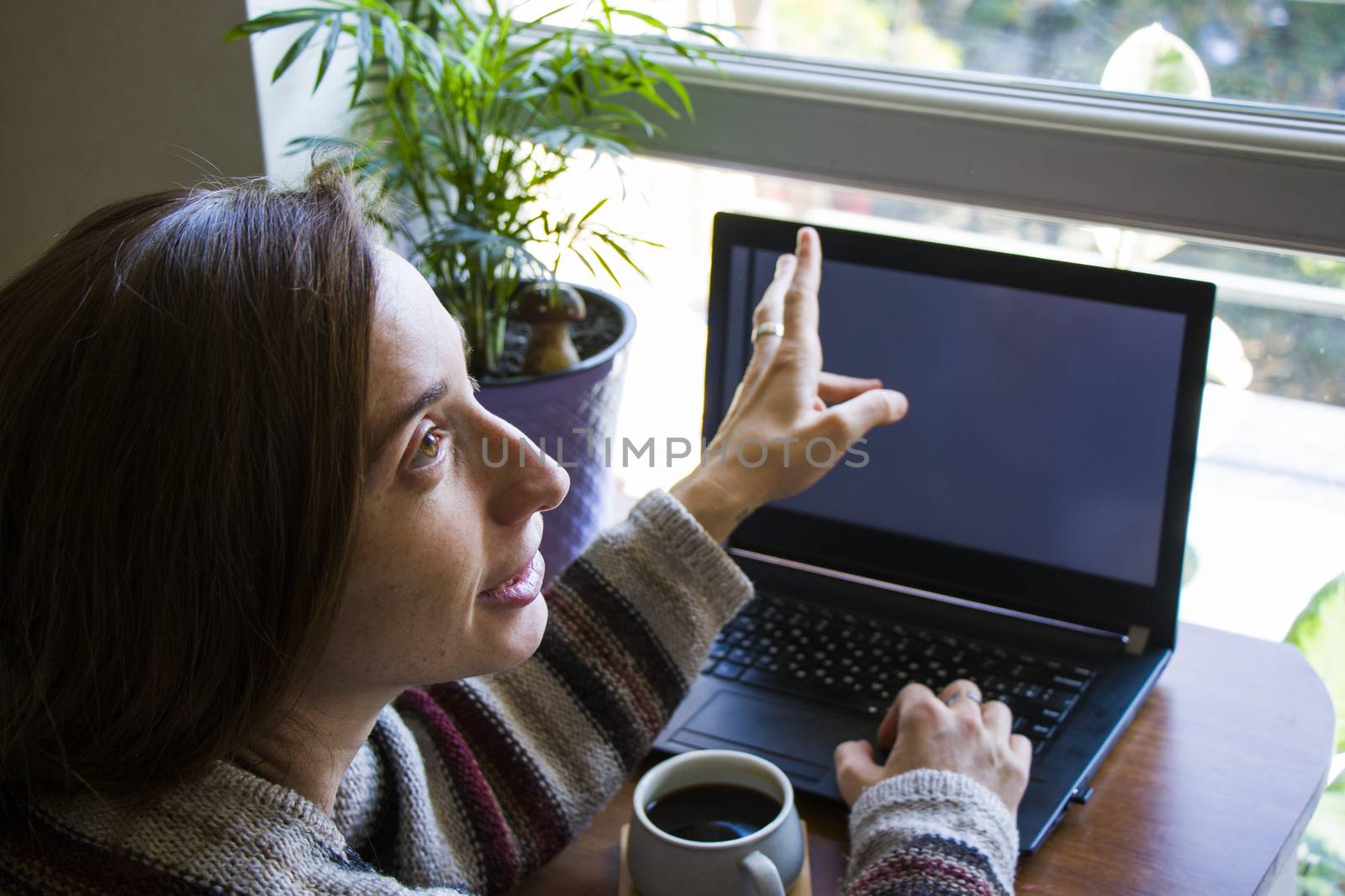 Woman working in office with digital tablet and notebook, writing and typing on the device