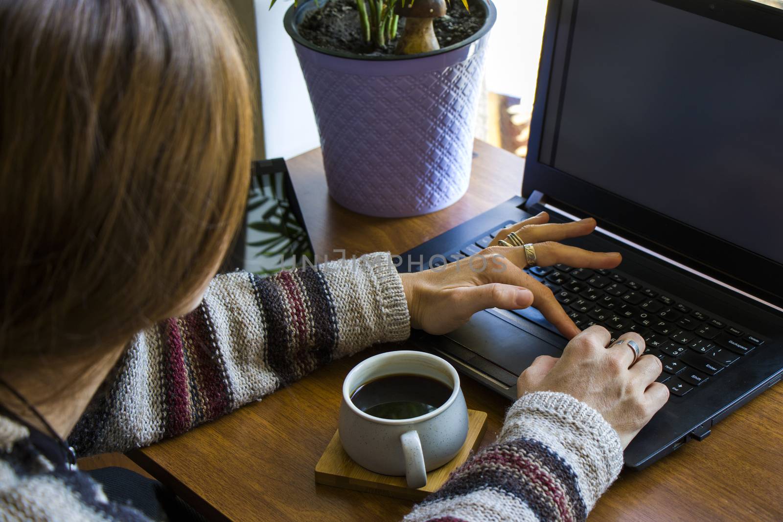 Woman working with notebook in workplace, digital tablet, mobile phone, coffee and plants in workspace, home working