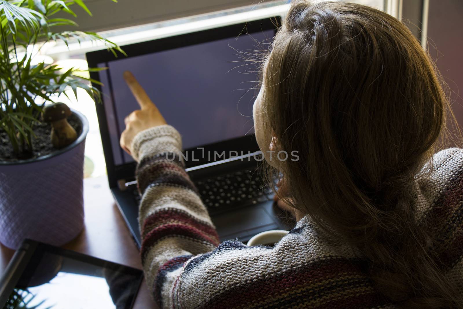 Woman working in office with digital tablet and notebook, writing and typing on the device