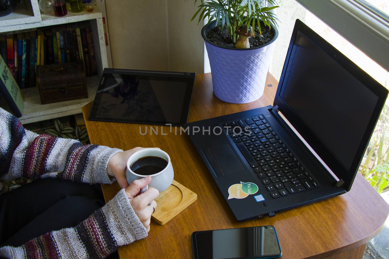 Tbilisi, Georgia - October 09, 2020: Woman working with notebook in workplace, digital tablet, mobile phone, coffee and plants in workspace, home working