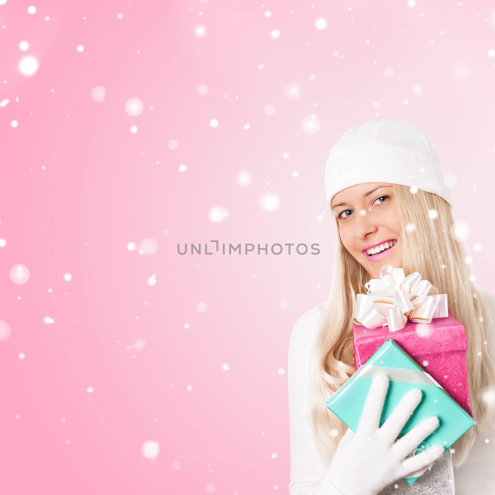 Happy woman holding Christmas gifts, pink background and snow glitter with copyspace, shopping and holidays