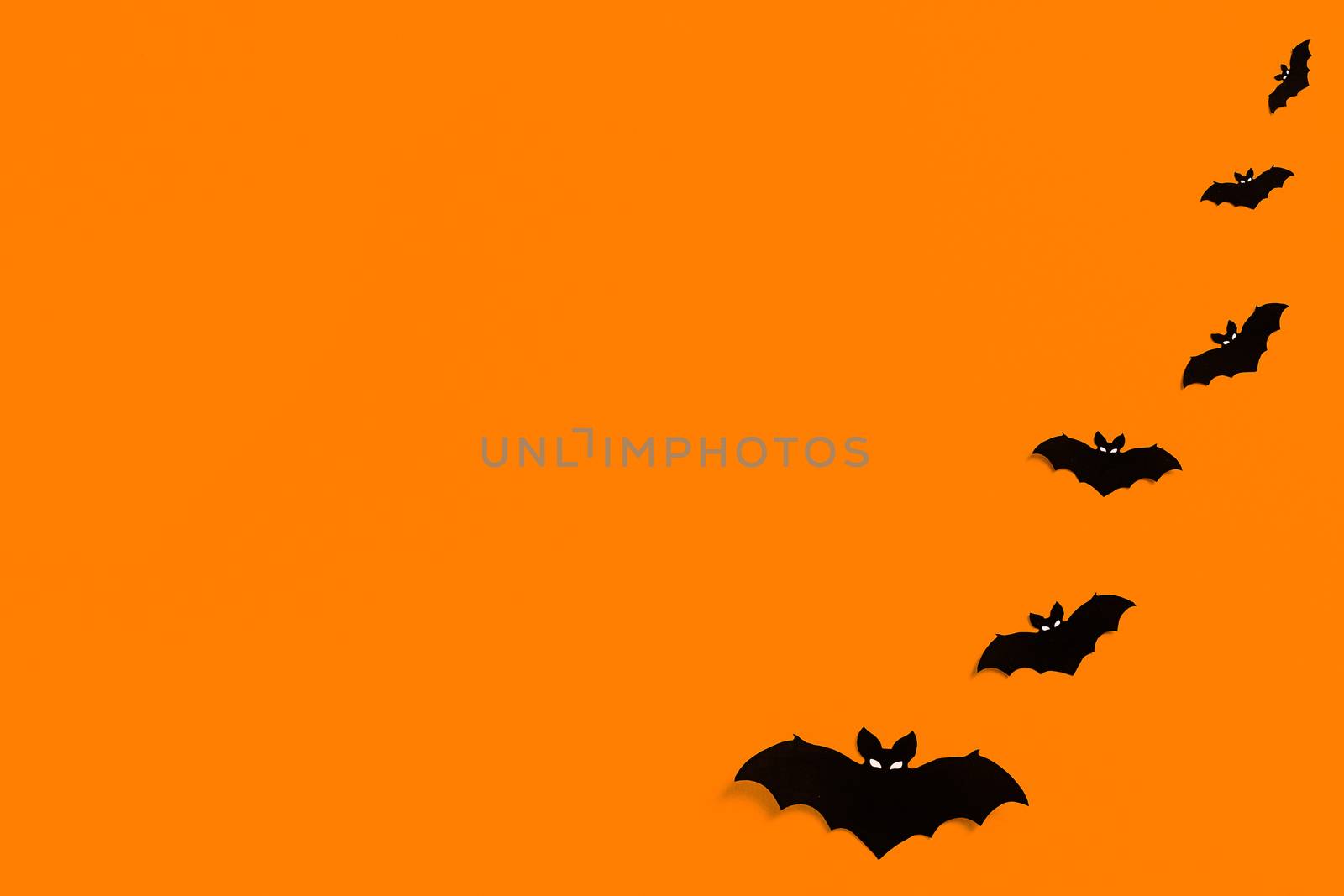 silhouettes of black paper bats on an orange background forming a frame, a flock of black bats on an orange background, Halloween concept, copy space. Flat lay for your design by Pirlik