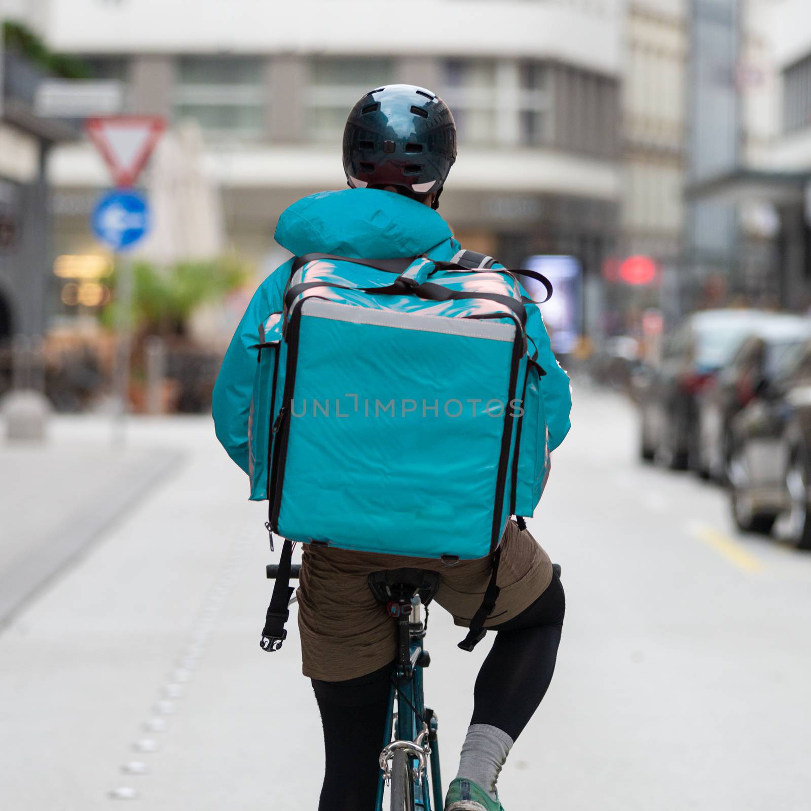 Unrecognizable courier on bicycle delivering food in cCity. Empty streets during shelter in place times during corona virus pandemic, 2020.