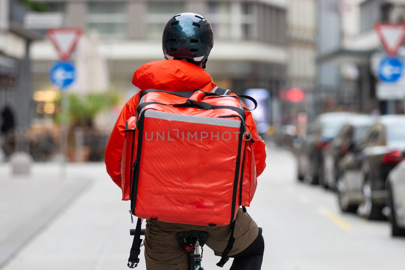 Unrecognizable courier on bicycle delivering food in cCity. Empty streets during shelter in place times during corona virus pandemic, 2020.
