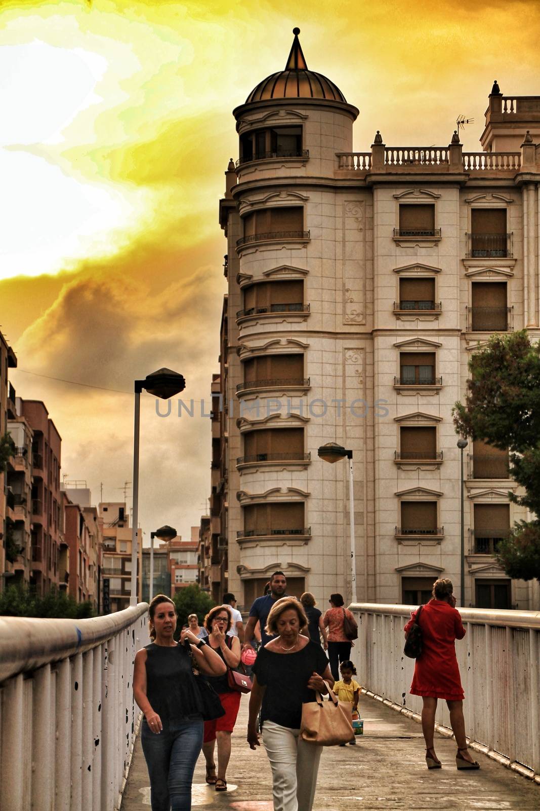 People crossing a bridge at sunset in Elche by soniabonet