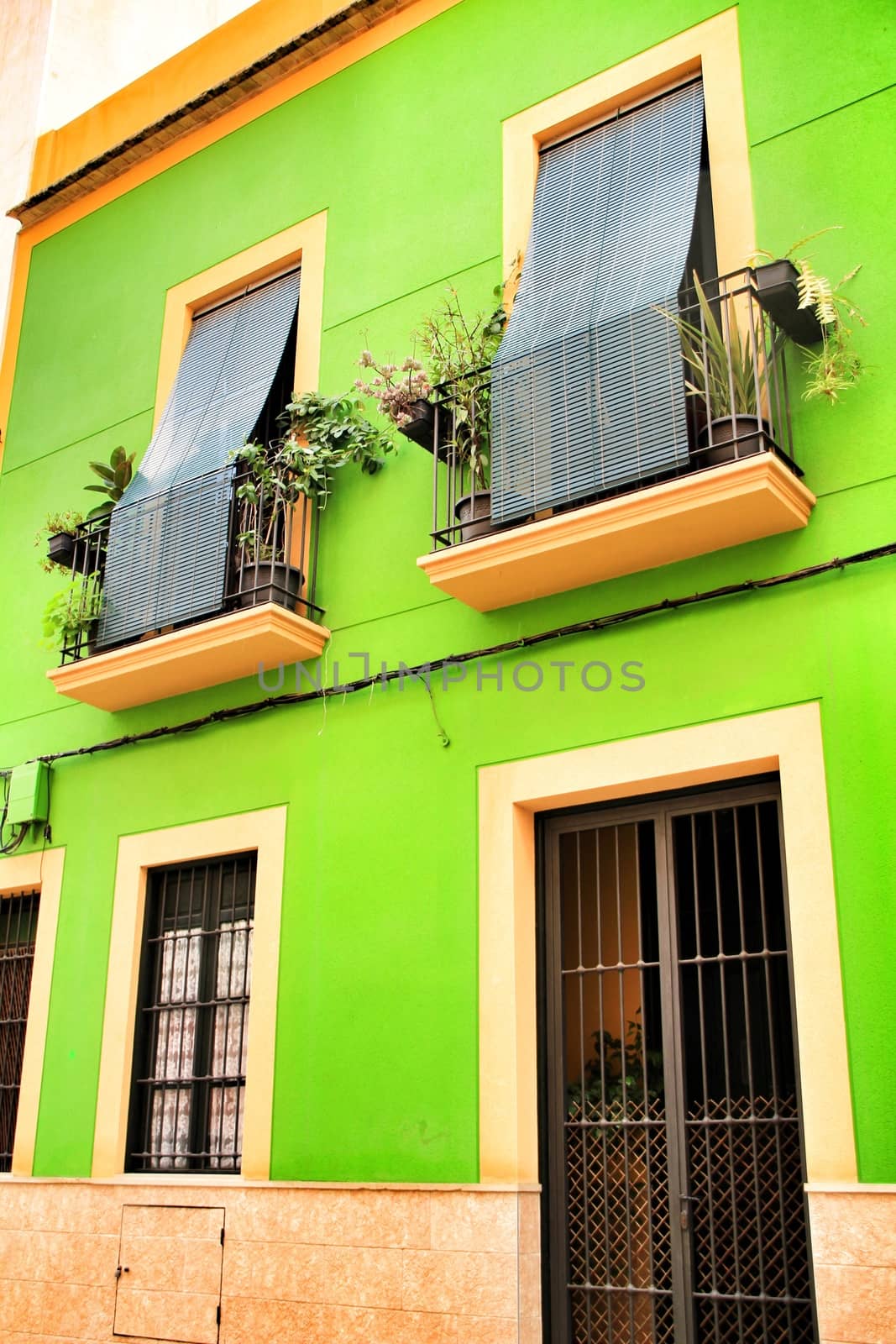 Elche, Alicante, Spain- September 9, 2020: Old colorful painted facades with vintage streetlight in Elche, Alicante, Spain. El Raval neighborhood.