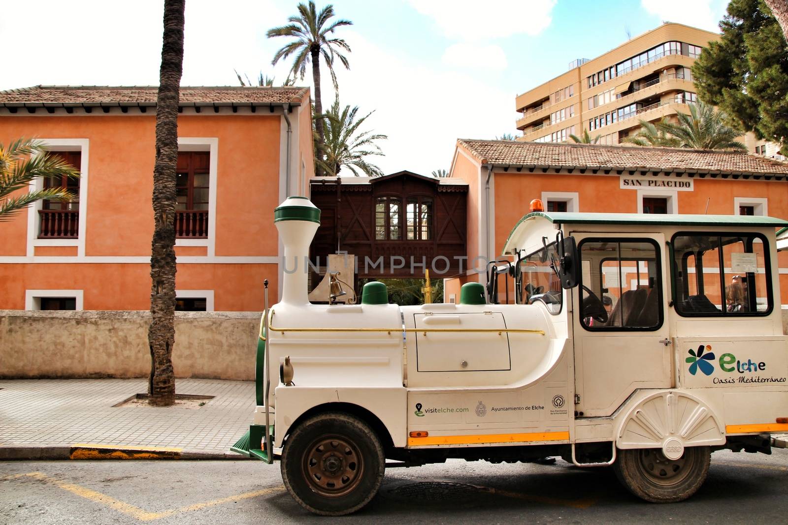 Elche, Alicante, Spain- February 14, 2019: Guided tour on Tourist train through the streets and palm groves in winter under blue sky
