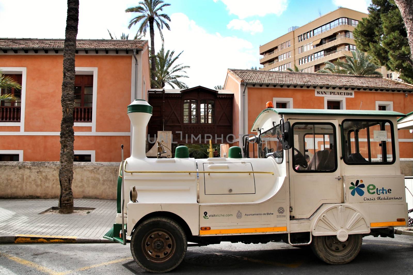 Elche, Alicante, Spain- February 14, 2019: Guided tour on Tourist train through the streets and palm groves in winter under blue sky