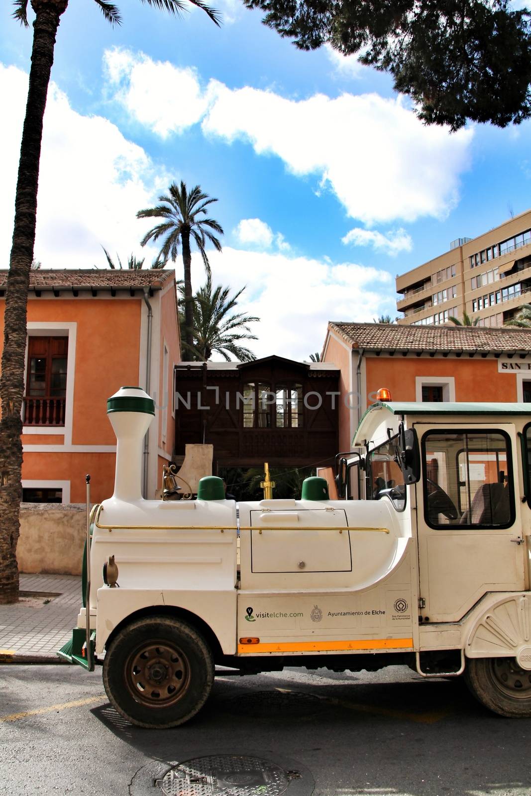 Elche, Alicante, Spain- February 14, 2019: Guided tour on Tourist train through the streets and palm groves in winter under blue sky