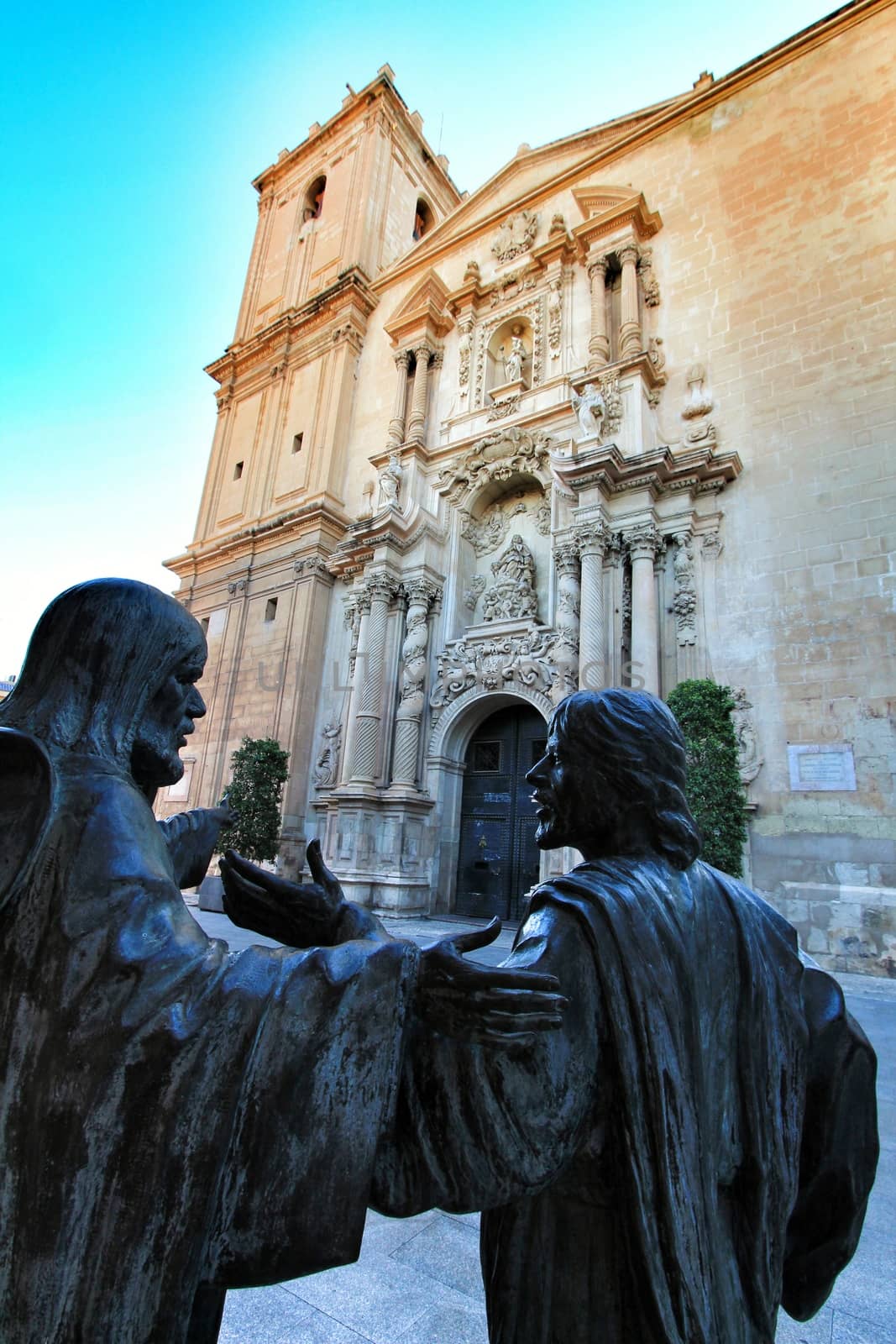 Elche, Alicante, Spain- September 9, 2020: Sculptures of three apostles. Main entrance and beautiful Valencian baroque facade of Santa Maria church dedicated to the Lady of the Assumption