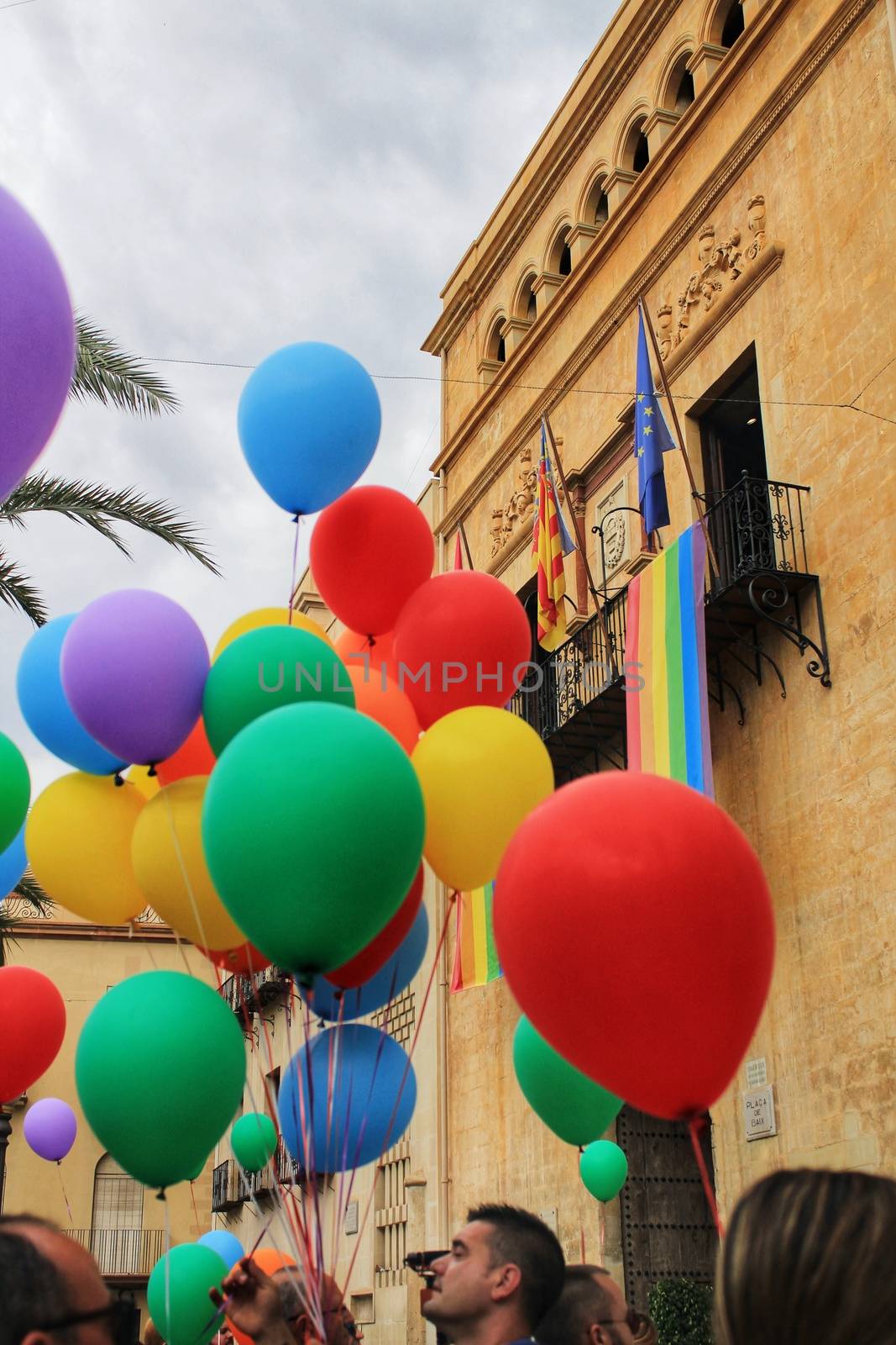 Rainbow flag hanging in the town hall and colorful balloons by soniabonet