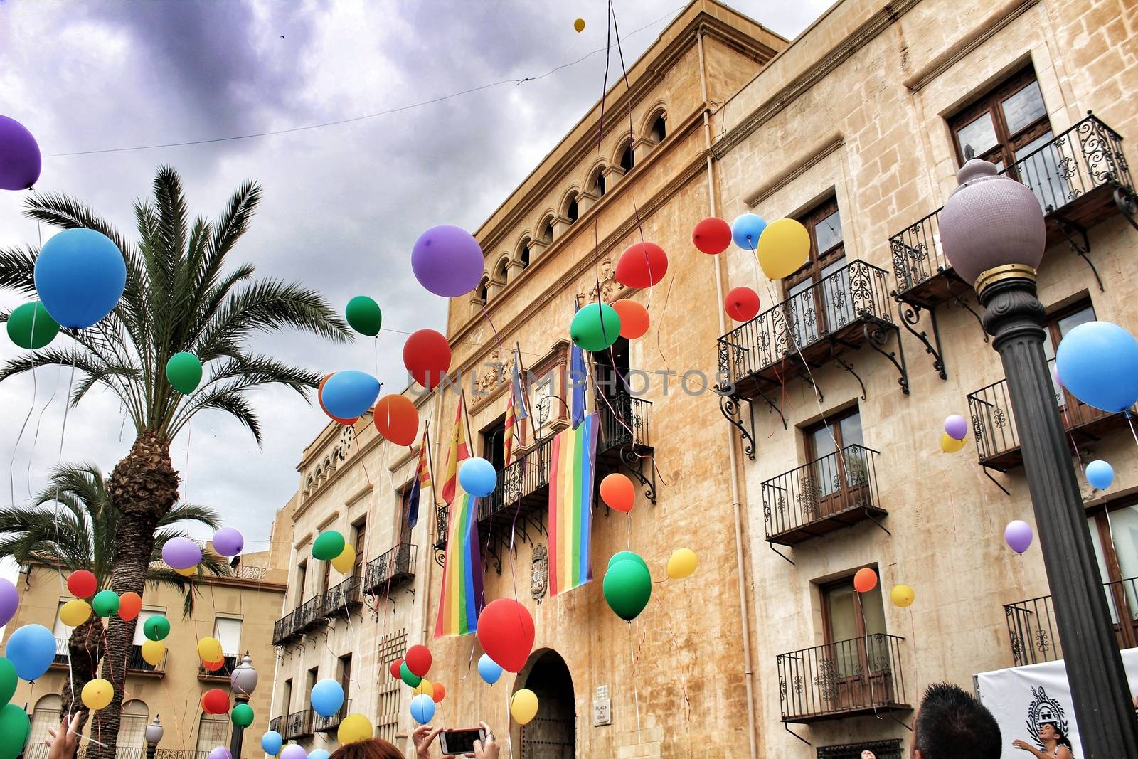 Rainbow flag hanging in the town hall and colorful balloons by soniabonet