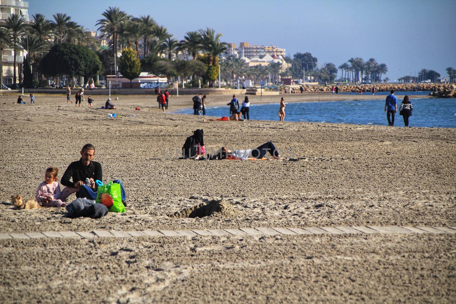 Santa Pola, Alicante, Spain- December 6, 2018: People enjoying and relaxing a sunny day of winter on the beach in Santa Pola, Spain.