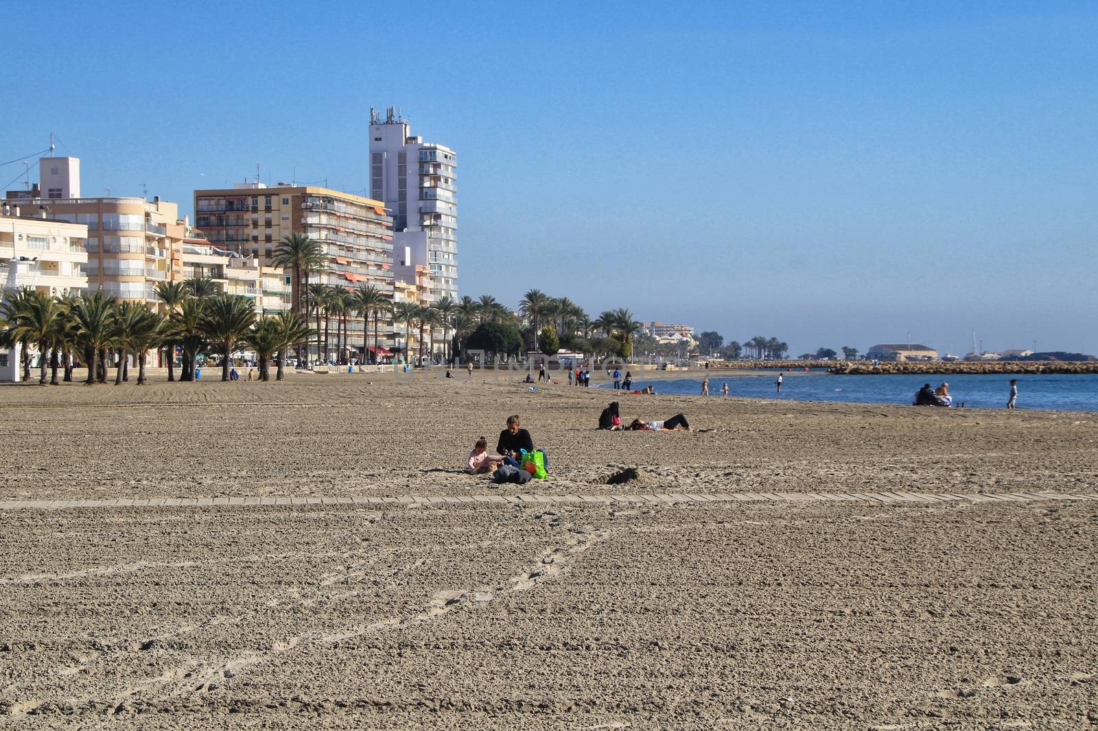 Santa Pola, Alicante, Spain- December 6, 2018: People enjoying and relaxing a sunny day of winter on the beach in Santa Pola, Spain.