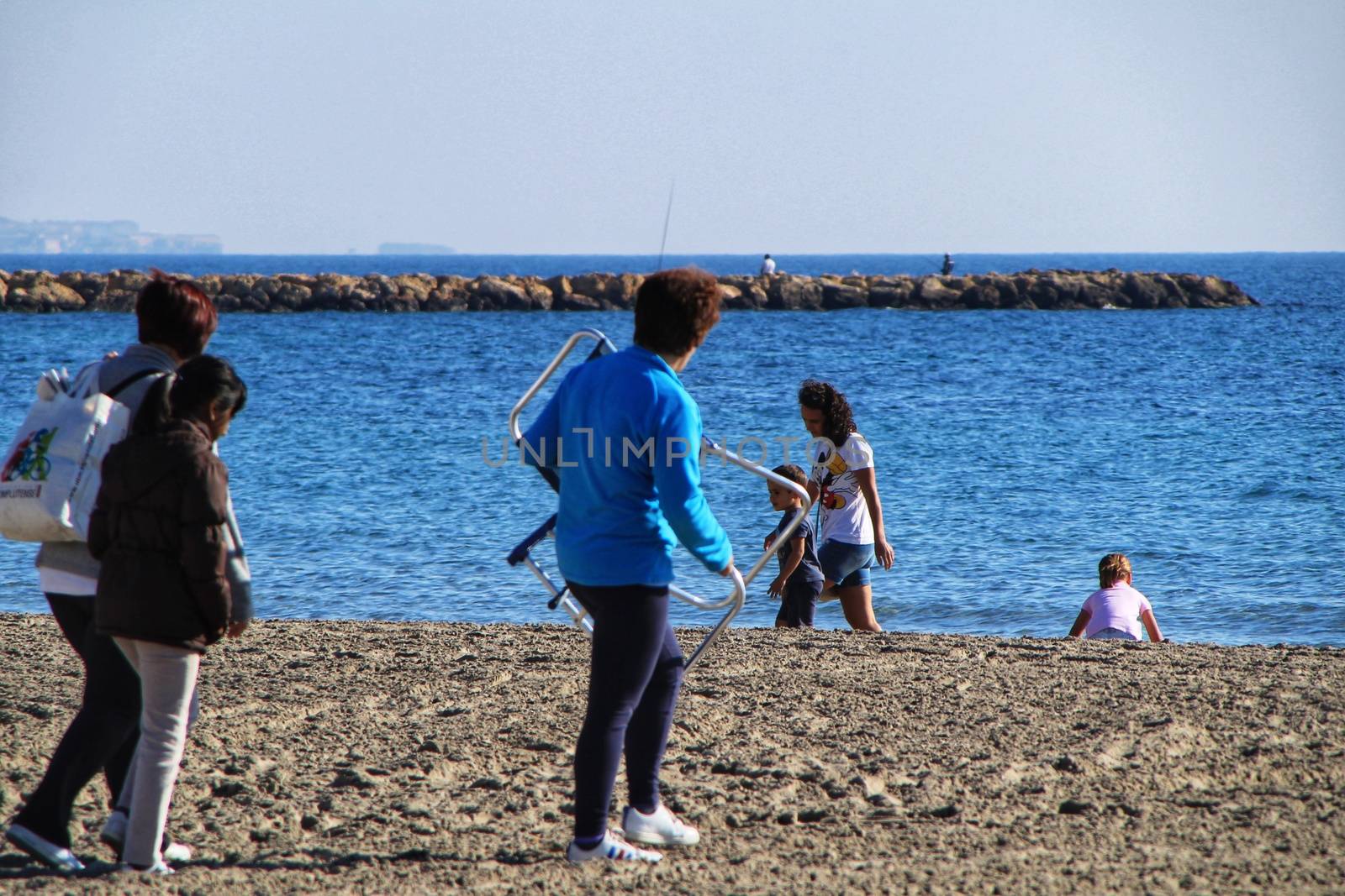 Santa Pola, Alicante, Spain- December 6, 2018: People enjoying and relaxing a sunny day of winter on the beach in Santa Pola, Spain.