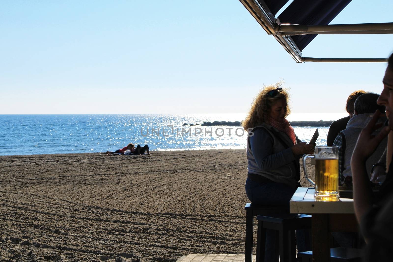 Santa Pola, Alicante, Spain- December 6, 2018: People enjoying and relaxing a sunny day of winter on the beach in Santa Pola, Spain.