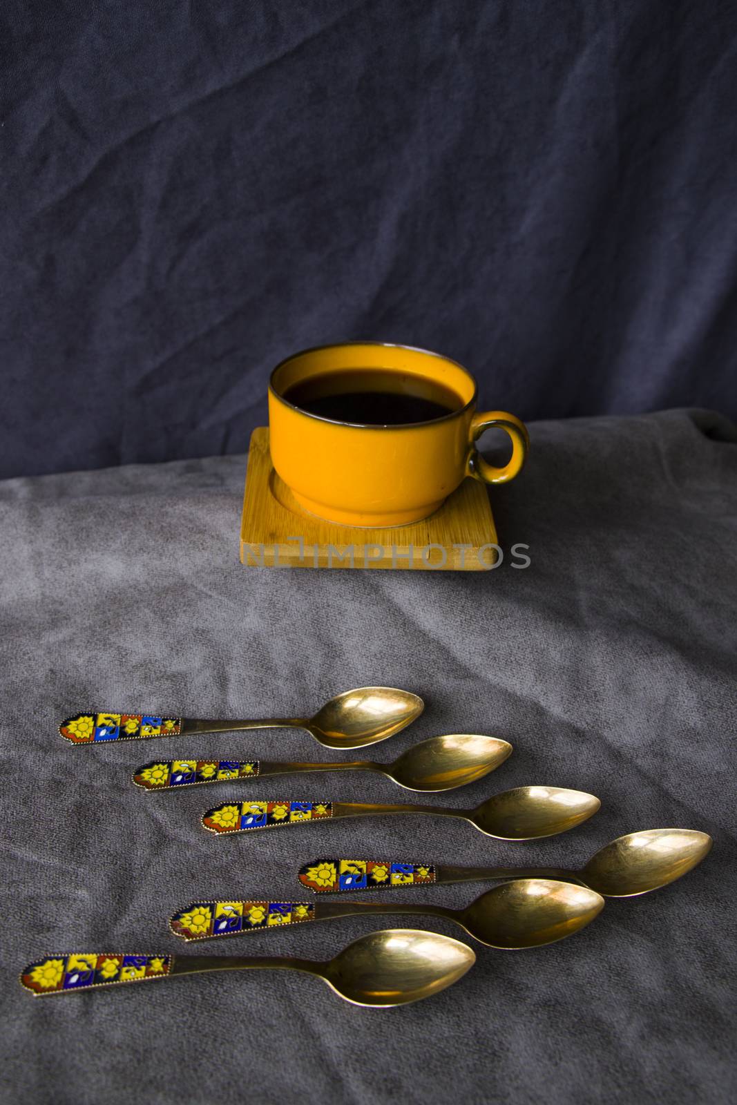 Vintage spoons, silverware, black coffee cup on the table by Taidundua