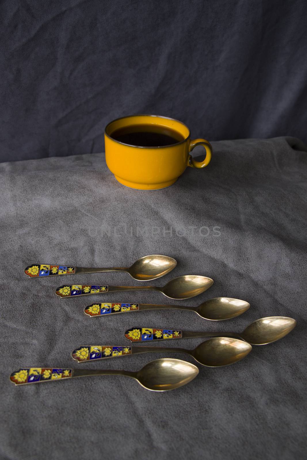 Vintage spoons, silverware, black coffee cup on the table by Taidundua