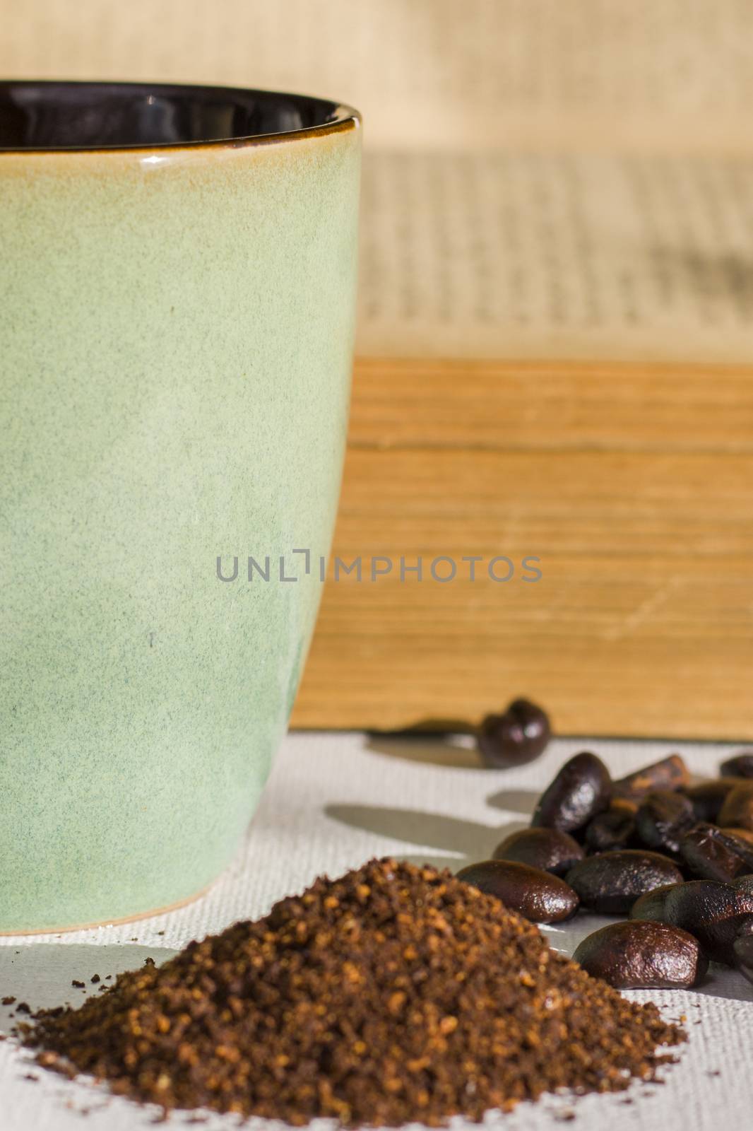 Roasted coffee beans and grained coffee seeds, studio shot, book and cup