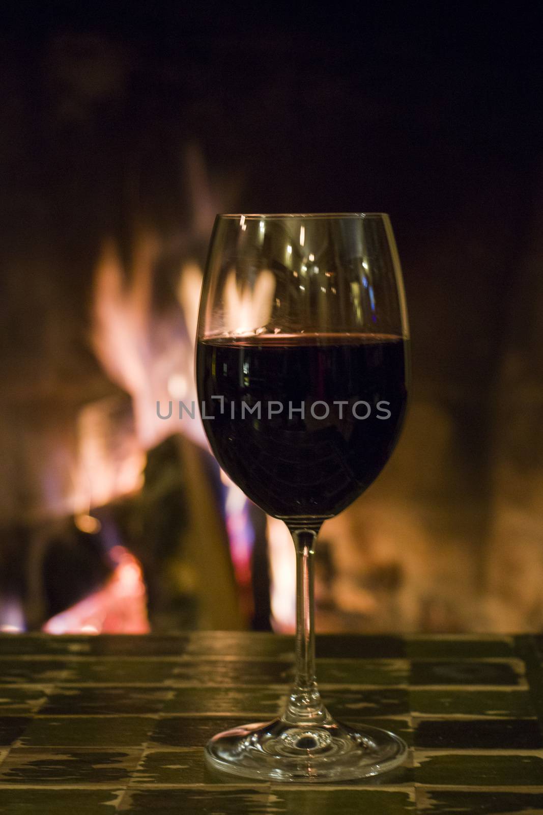 Full wine glass on the table and fireplace background in the bar