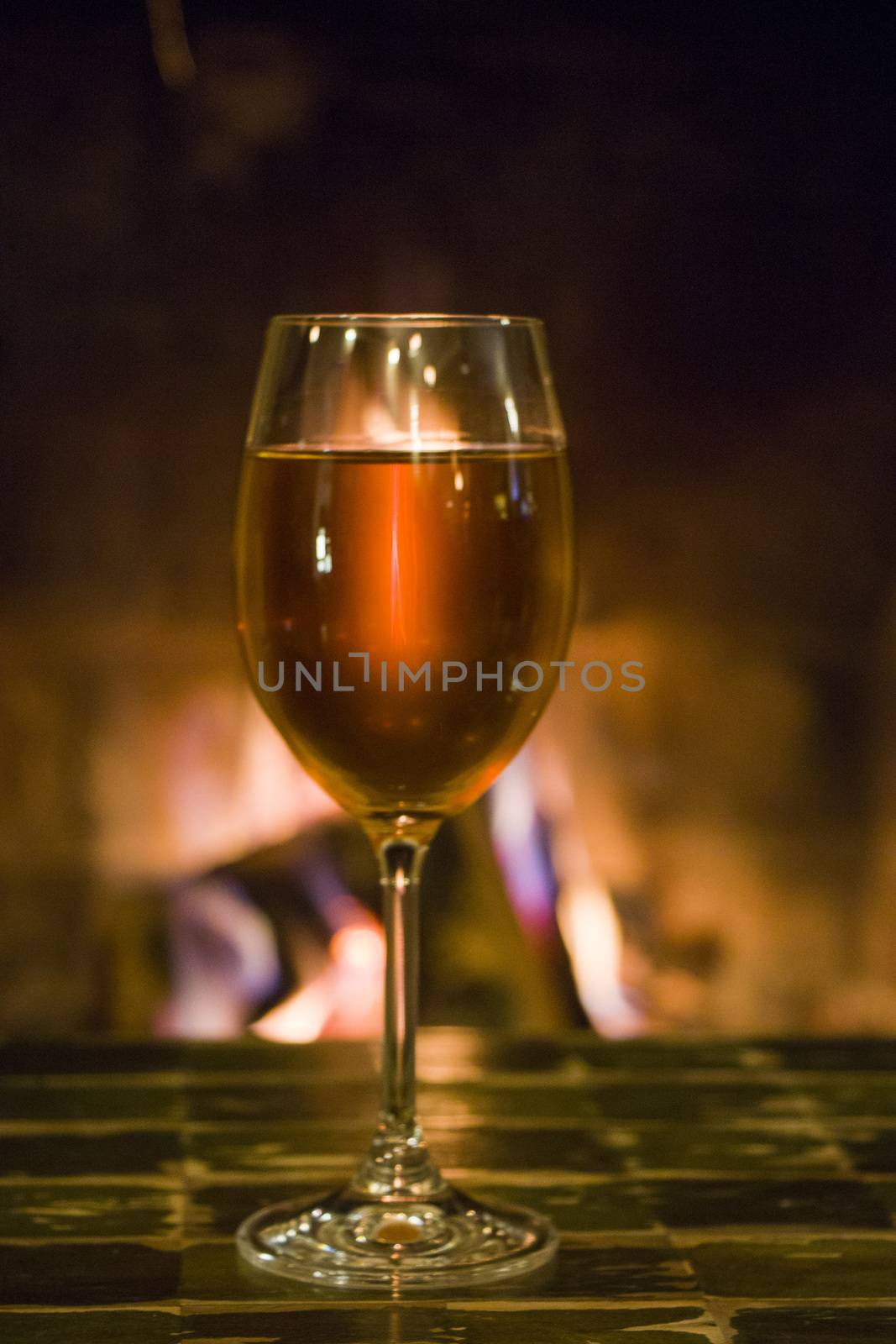 Full wine glass on the table and fireplace background in the bar