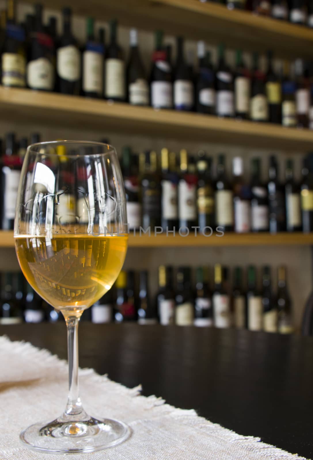 Full white wine glass on the table, wine bottle background, wine magazine and shop in restaurant and bar. by Taidundua