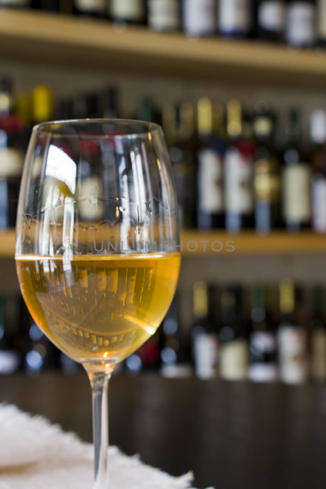 Full white wine glass on the table, wine bottle background, wine magazine and shop in restaurant and bar. Georgian wine in Tbilisi.