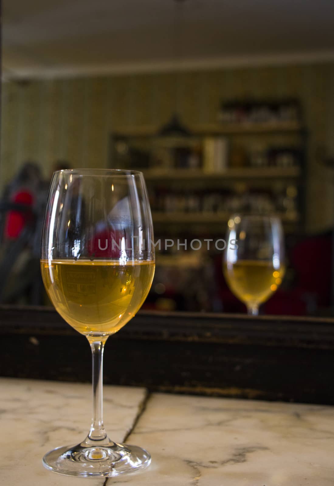Full white wine glass on the table, wine bottle background, wine magazine and shop in restaurant and bar. Georgian wine in Tbilisi.