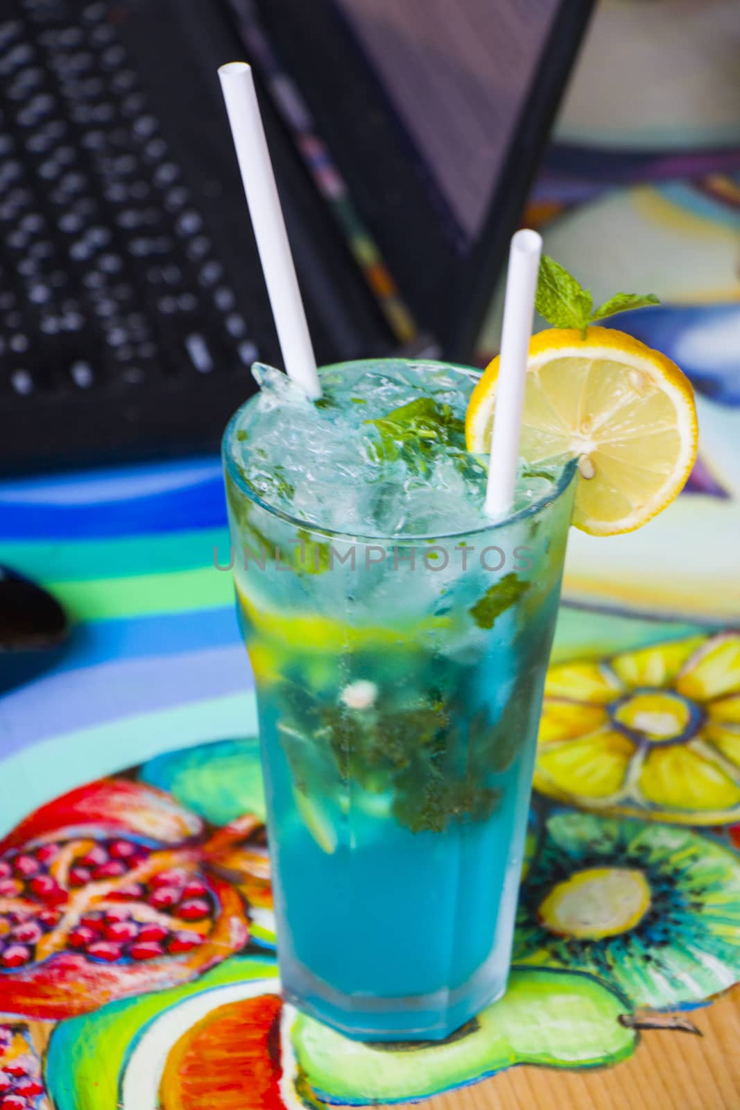 Blue cocktail with curacao and citruses and notebook background, working space. Alcoholic drink. Summer holidays. by Taidundua