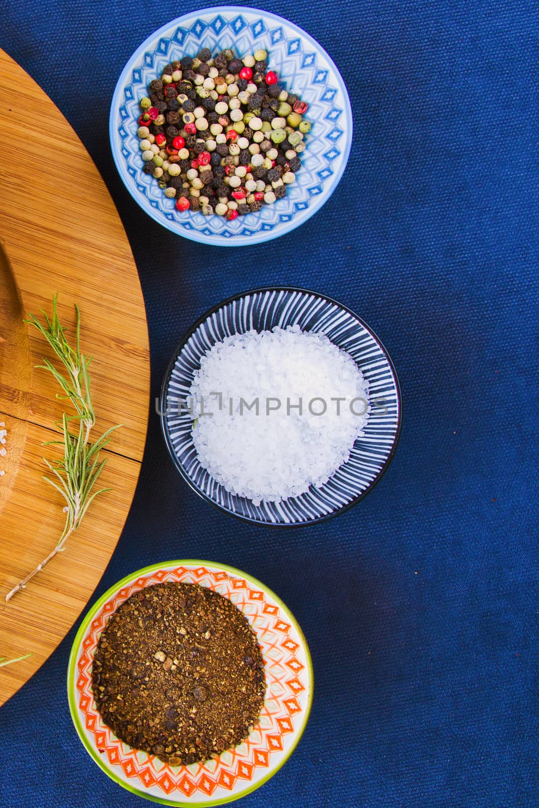 Coarse salt, black, red and white pepper in the bowl and on the board