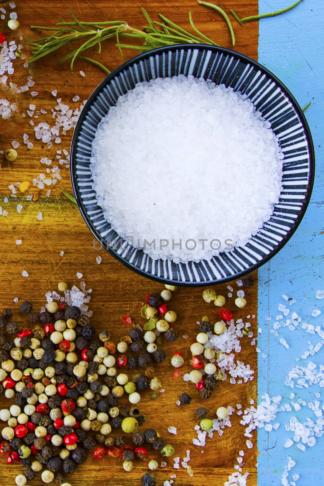 Coarse salt, black, red and white pepper in the bowl and on the board