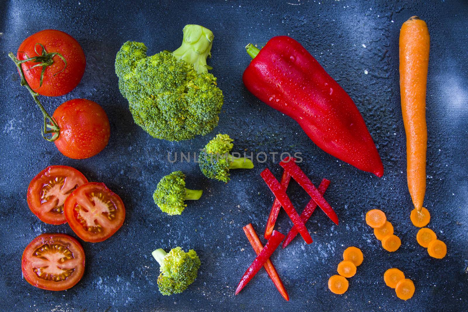 Chopped and cut vegetables on the board, carrot, bell pepper, tomato, broccoli by Taidundua