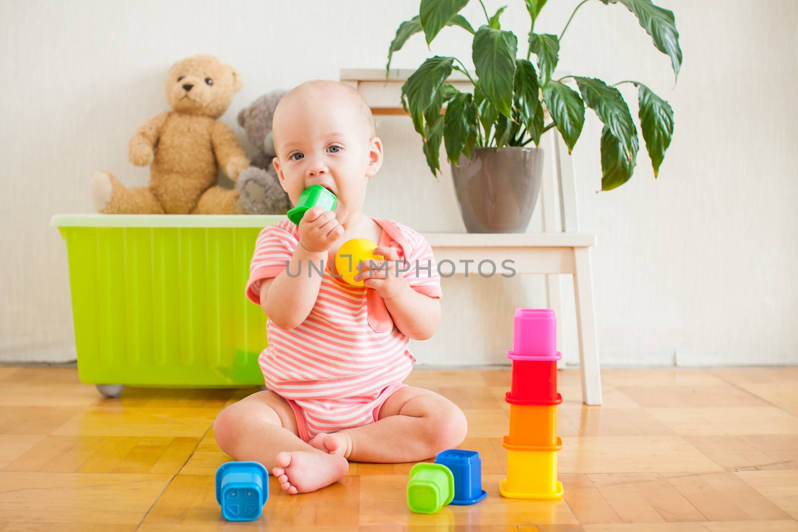 Little baby girl sitting on the floor, crawling and playing with brightly colored educational toys by malyshkamju