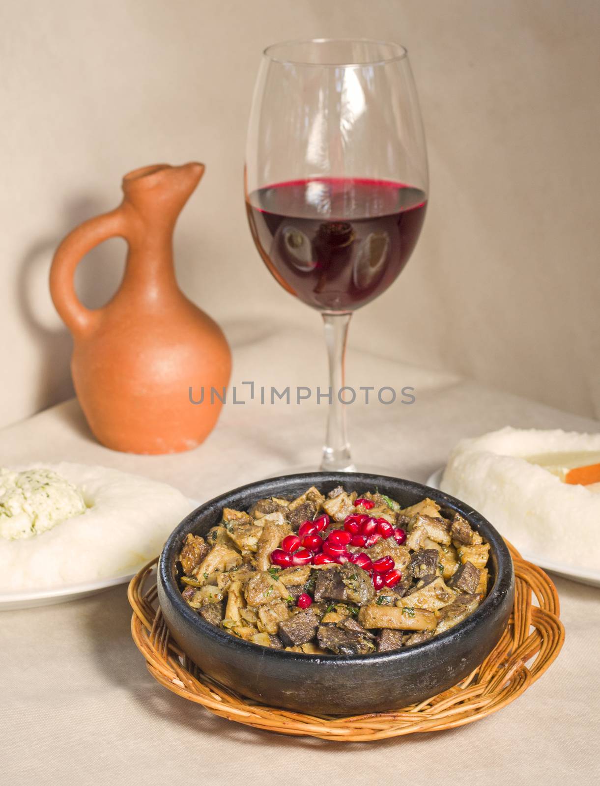 Kuchmachi, Georgian traditional food with meat, walnuts, pomegranates and onion, near red wine and ghomi with cheese.