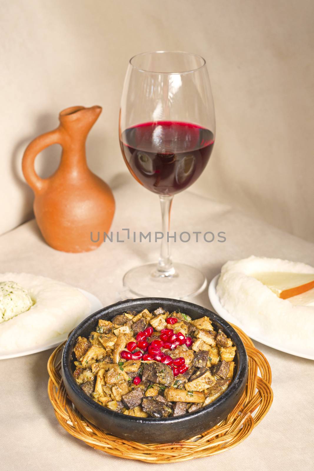 Kuchmachi, Georgian traditional food with meat, walnuts, pomegranates and onion, near red wine and ghomi with cheese.