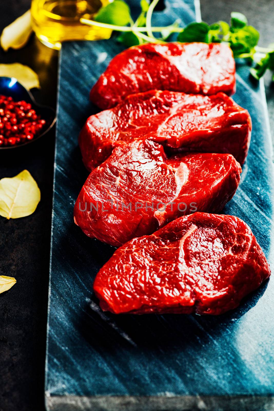 Beef steaks on cutting board with herbs and spices