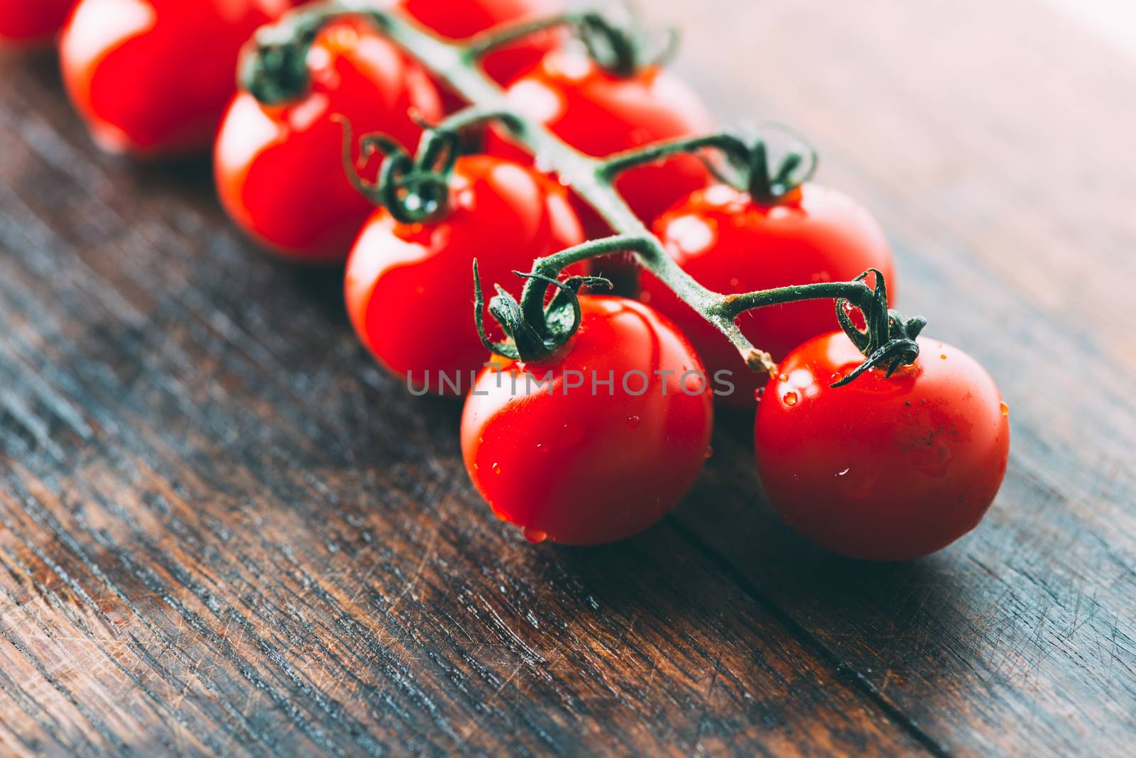 Cherry tomatoes on wooden table by Nanisimova