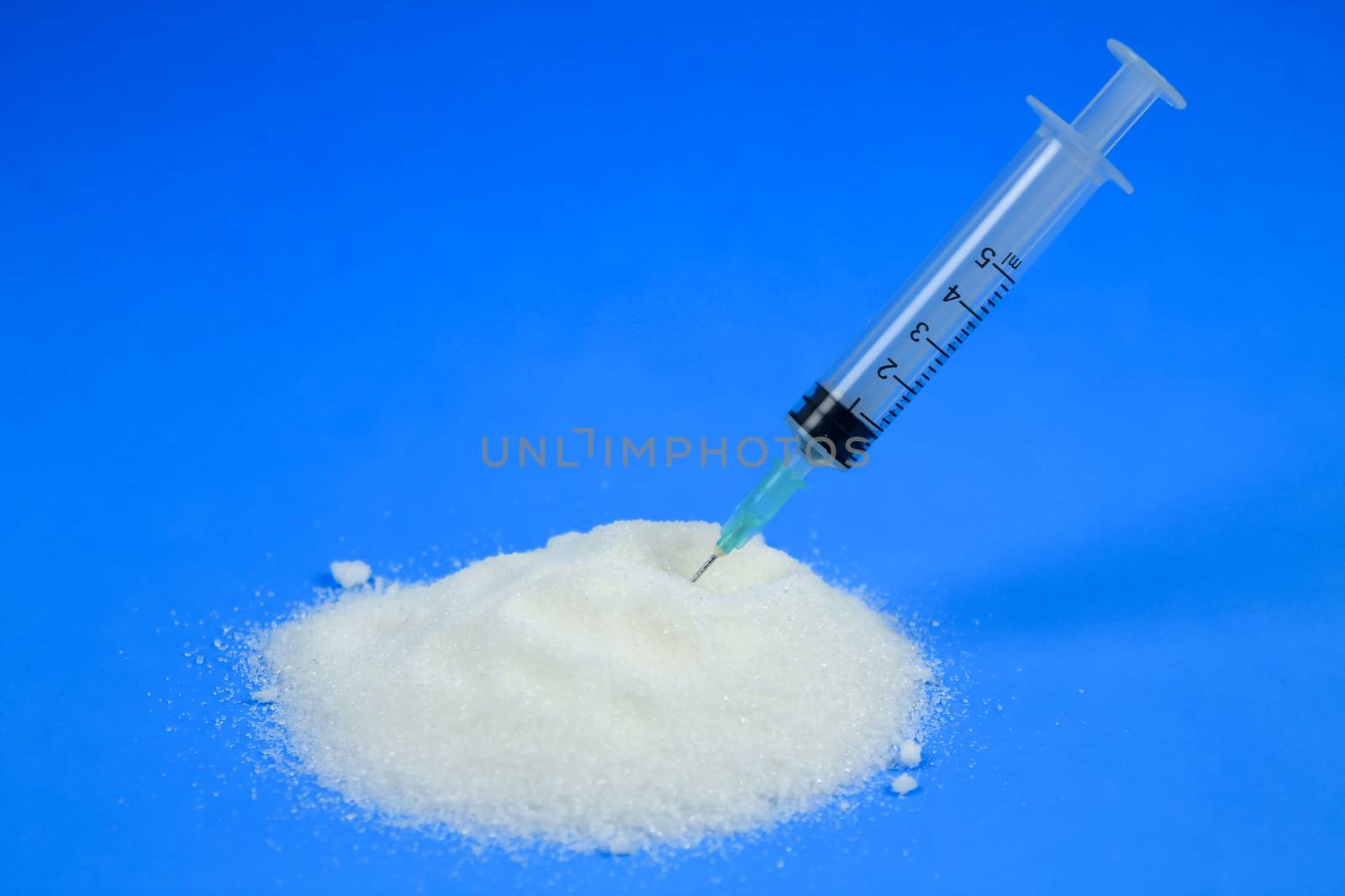 Conceptual photo of syringe and sugar emulating sugar addiction