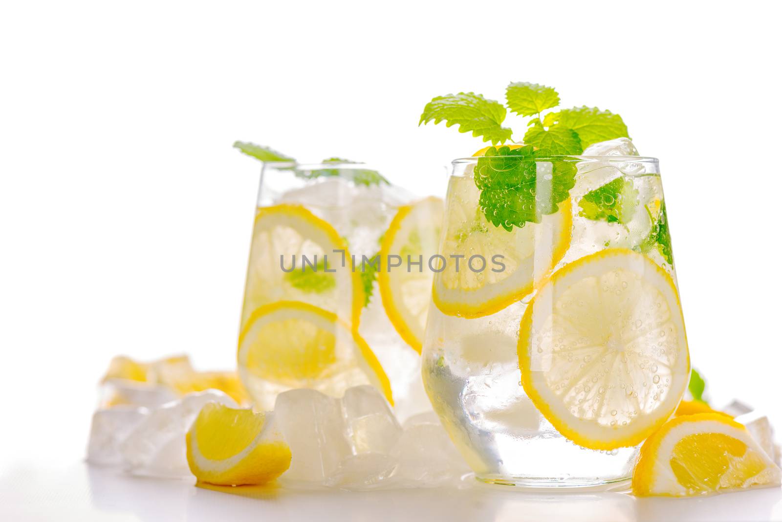 Lemonade drink in a glass: water, ice, lemon slice and mint on white background