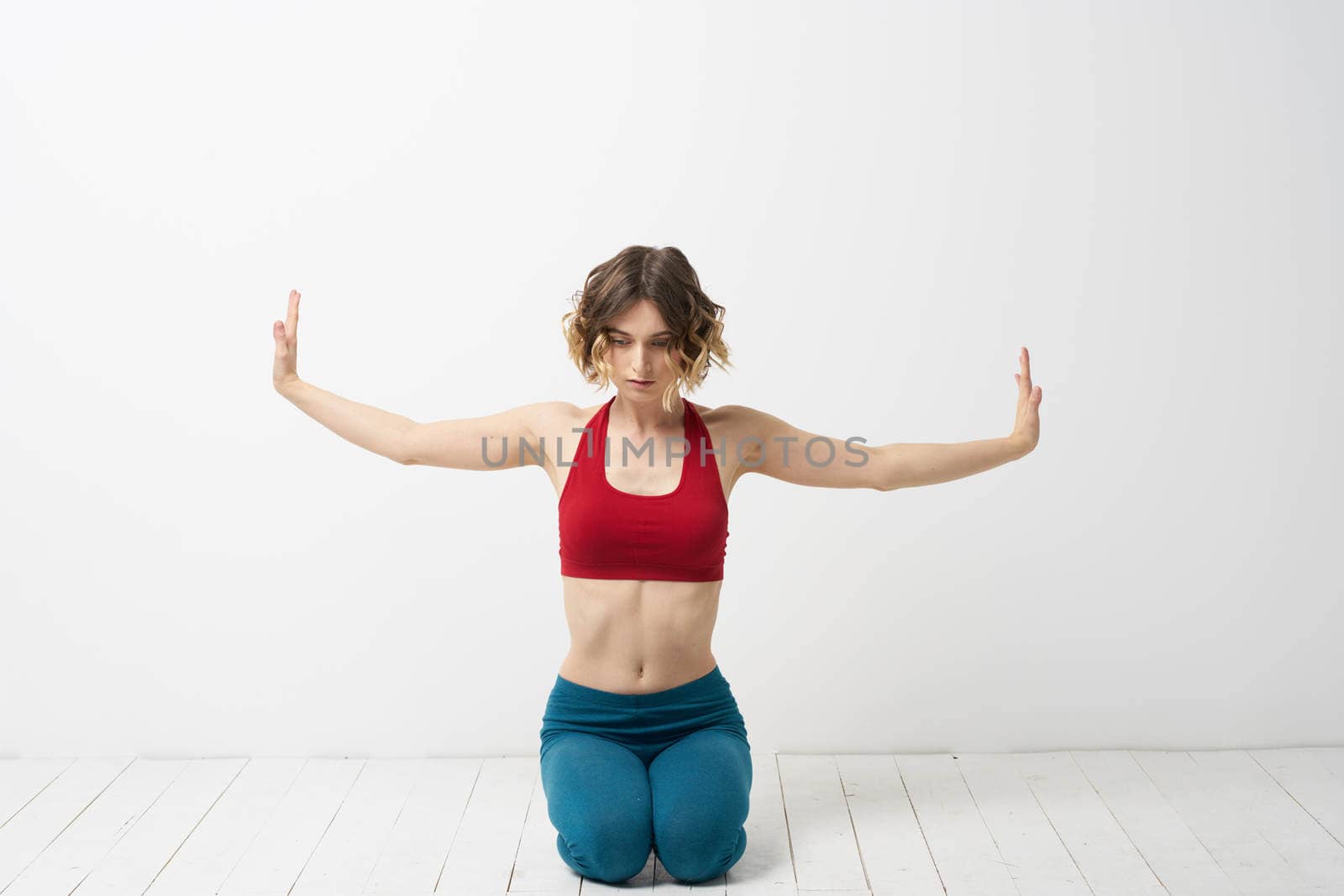 the girl is engaged in yoga on a light background Red T-shirt gesticulating with his hands. High quality photo