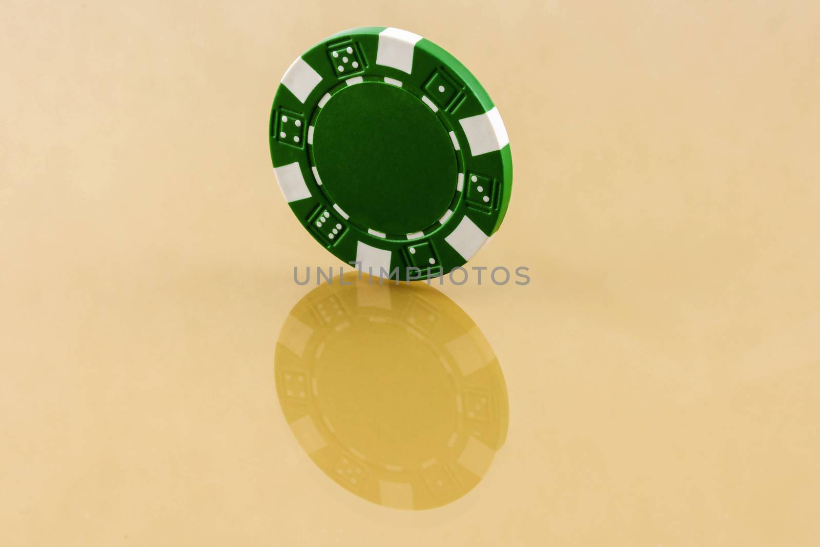 Green casino chip is worth an edge on the reflective surface by Grommik