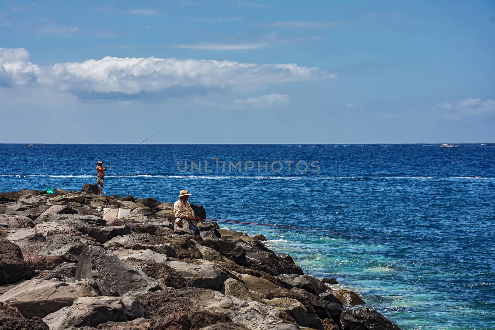 Two men fishing in the sea with a rocky shore by Grommik