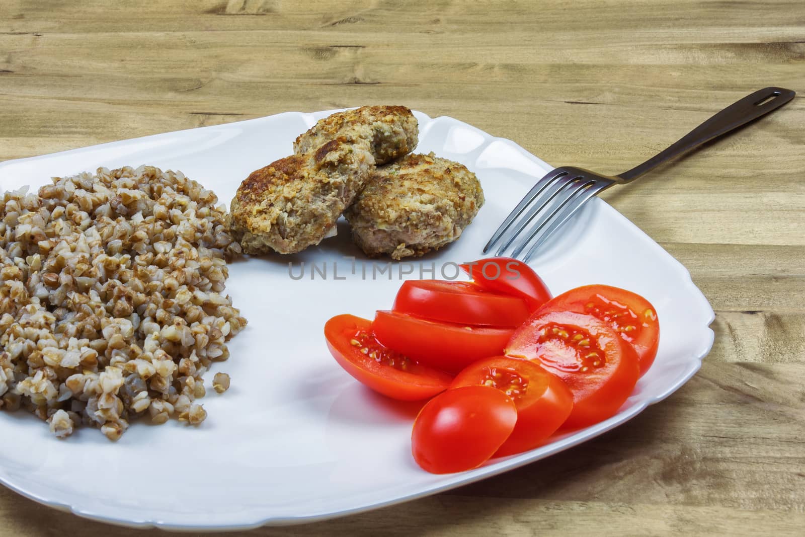 On a square plate is buckwheat porridge with meat cutlets and ch by Grommik