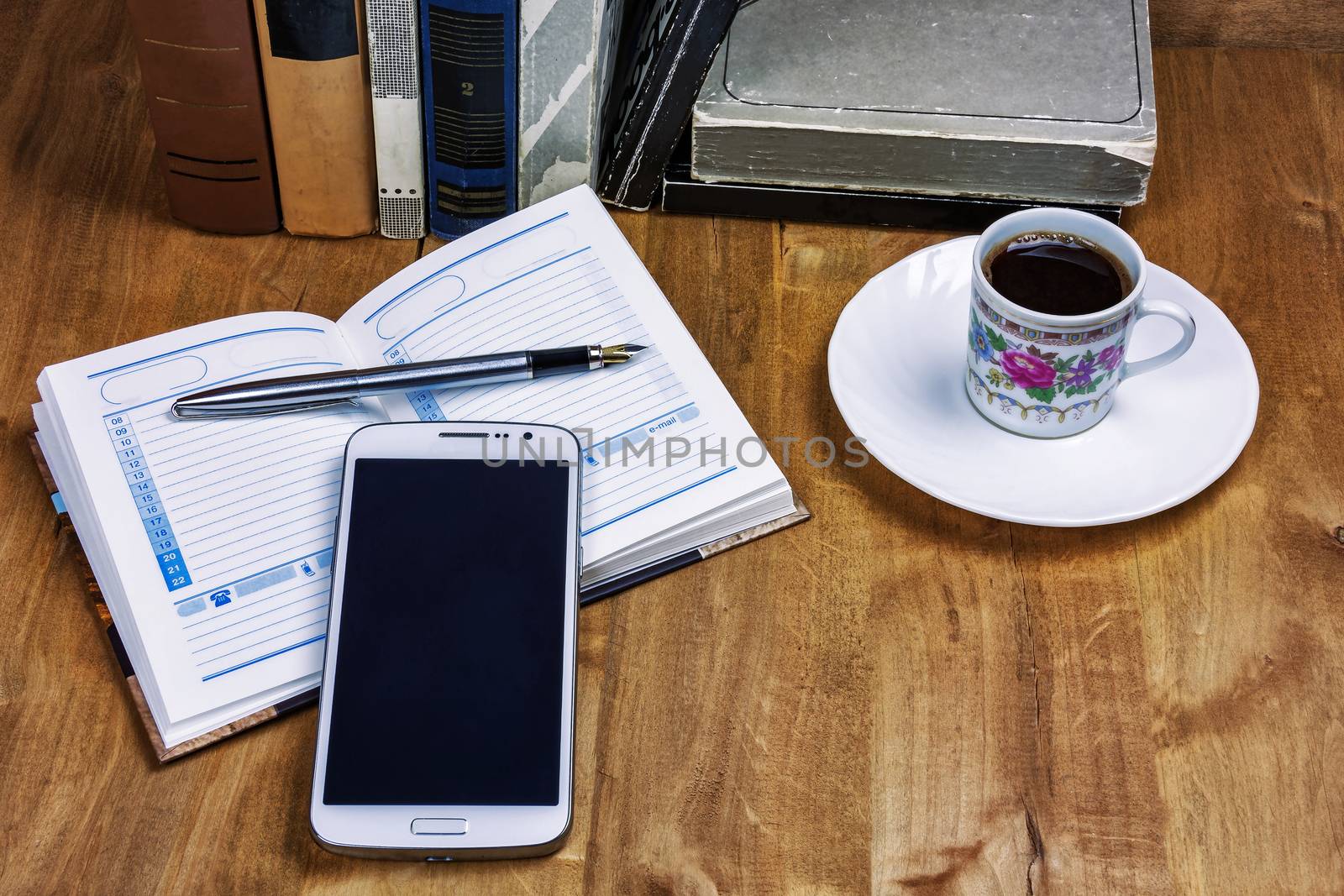 Books, a cup of coffee, a diary with a pen and a smartphone on t by Grommik