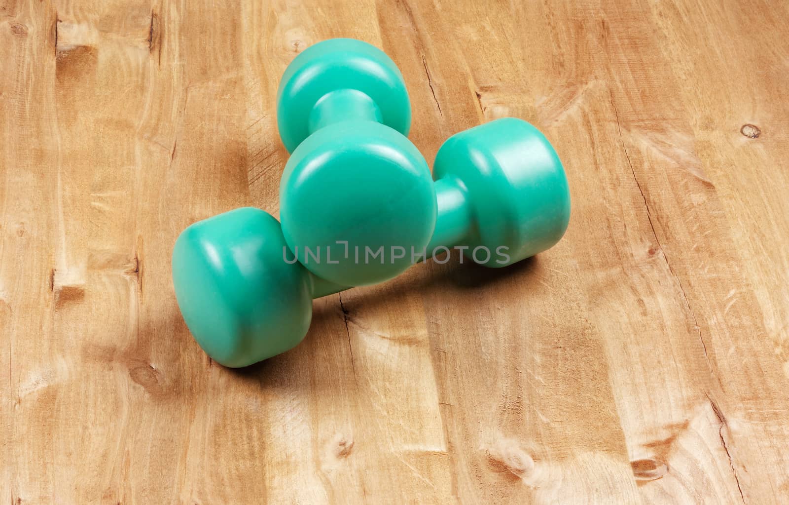 Two dumbbells for playing sports lie on a wooden surface