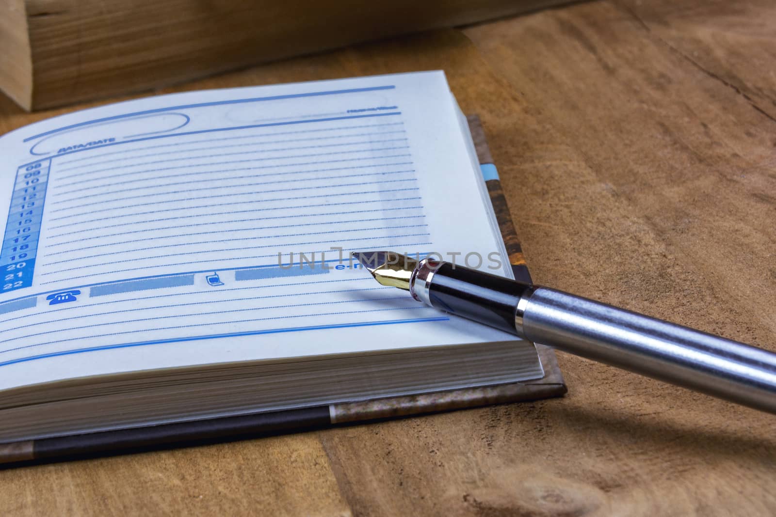 On the wooden surface is an open diary and fountain pen