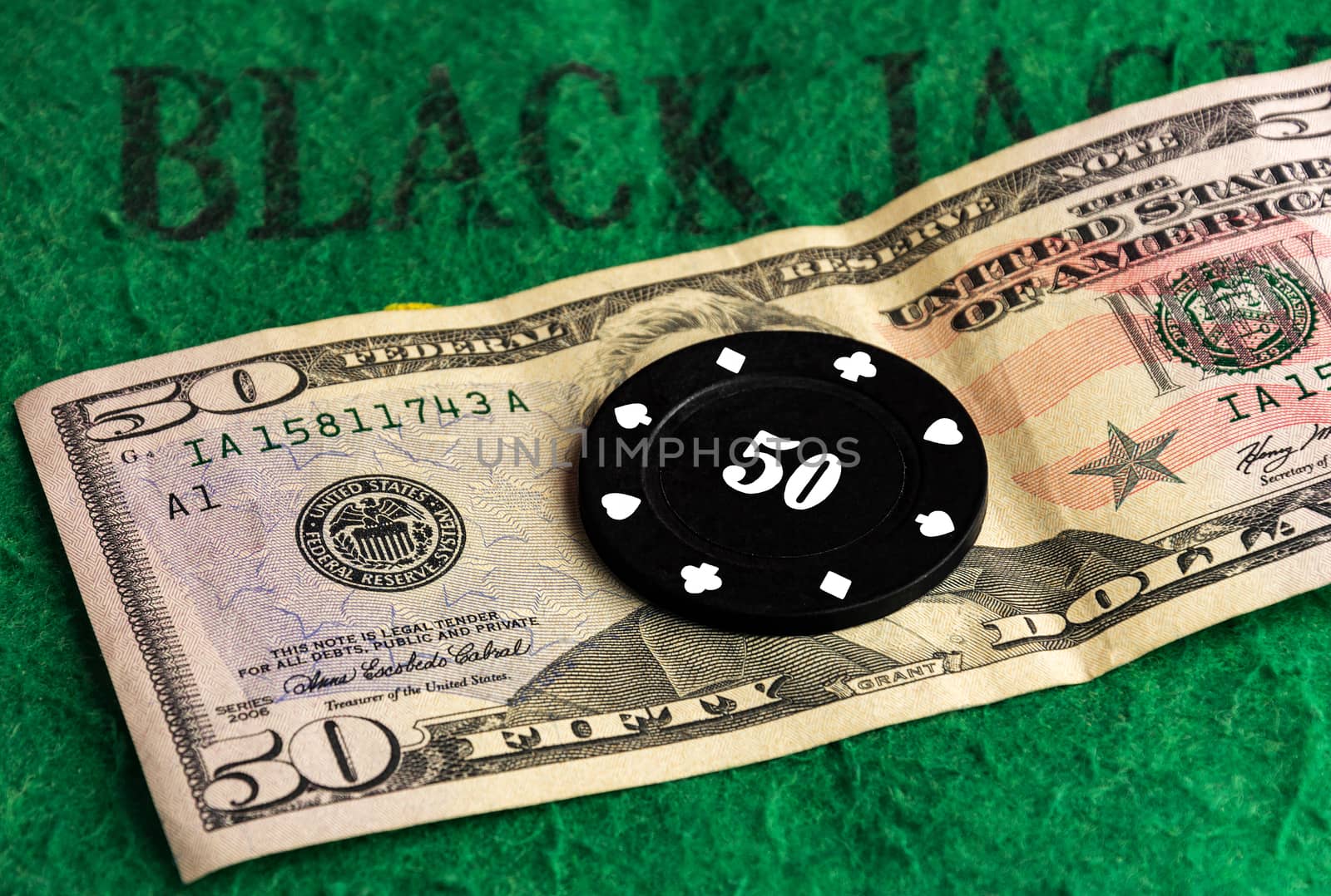 Black casino chip lies on a cash bill by Grommik