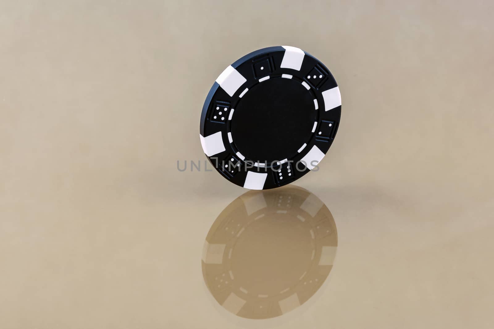 A black casino chip stands on the reflecting surface by Grommik