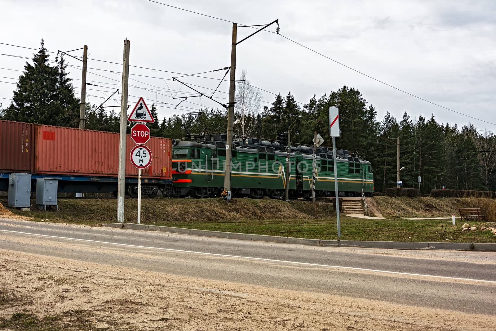 The locomotive of a freight train is crossing the railway crossi by Grommik